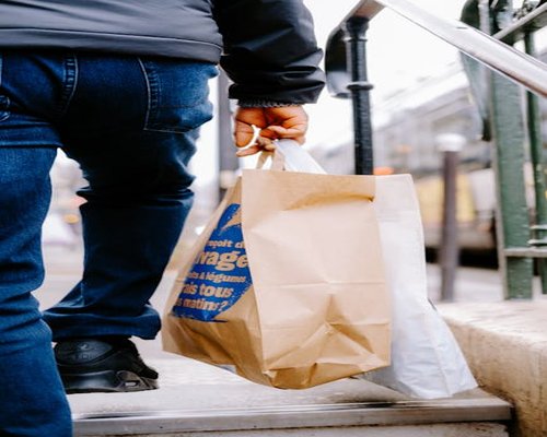 Person holding grocery bags walking in a city